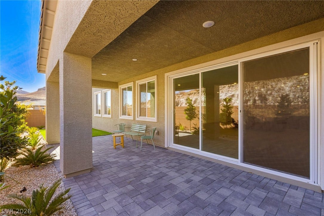 9986 Joshua Foothills Street, Las Vegas, NV 89178 A generously proportioned covered patio with pavers extends outdoor living space, set against a distant mountain landscape.