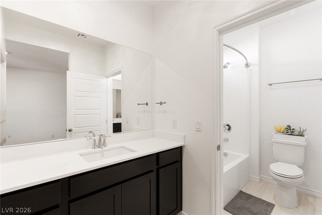 9986 Joshua Foothills Street, Las Vegas, NV 89178 A well-lit primary bathroom featuring a vanity with ample counter space and a convenient shower-over-tub.