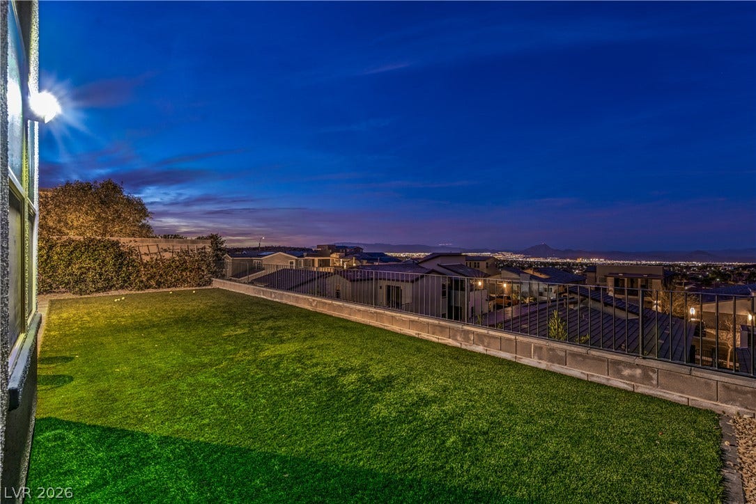 1984 Canyon Highlands Drive, Henderson, NV 89052 A neatly manicured lawn overlooks city lights from this elevated, fenced backyard at dusk.