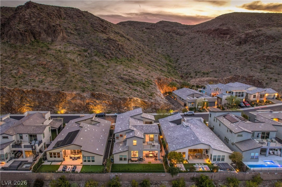 1984 Canyon Highlands Drive, Henderson, NV 89052 An aerial perspective reveals modern homes nestled against a rugged mountain landscape at dusk.