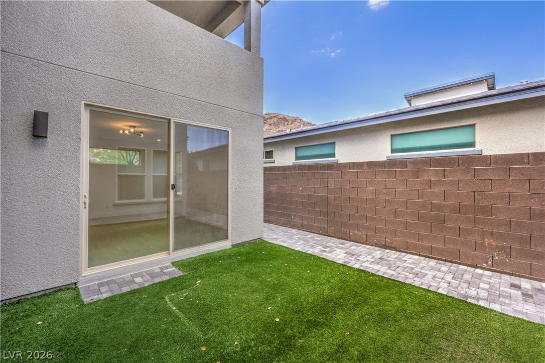 1984 Canyon Highlands Drive, Henderson, NV 89052 A private outdoor space with artificial turf and a paver walkway extends from a modern sliding glass door.