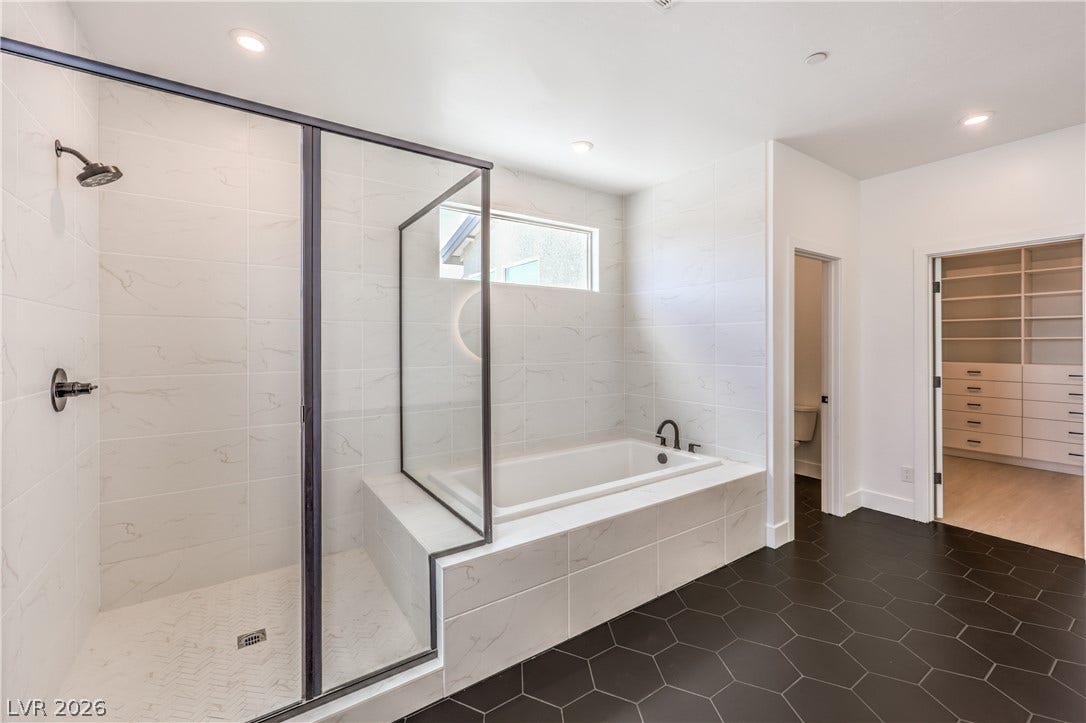 1984 Canyon Highlands Drive, Henderson, NV 89052 Luxurious bathing retreat boasts a sleek, glass-enclosed shower and a deep soaking tub, complemented by a convenient walk-in closet.