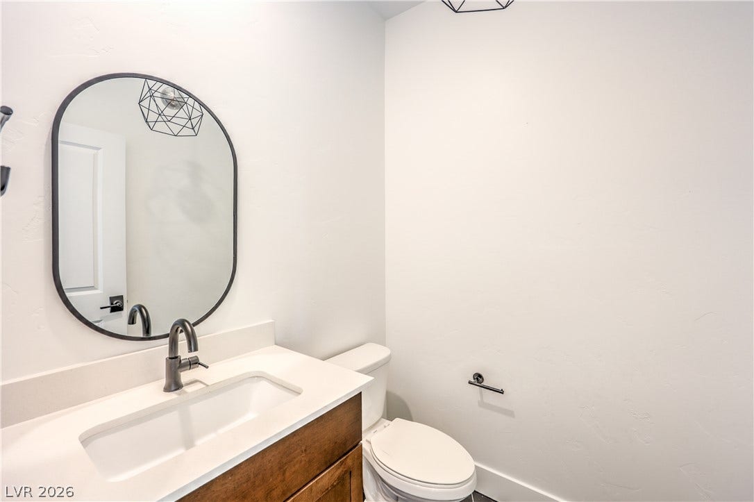 1984 Canyon Highlands Drive, Henderson, NV 89052 A well-appointed powder room features a modern vanity with a sleek oval mirror and contemporary lighting.