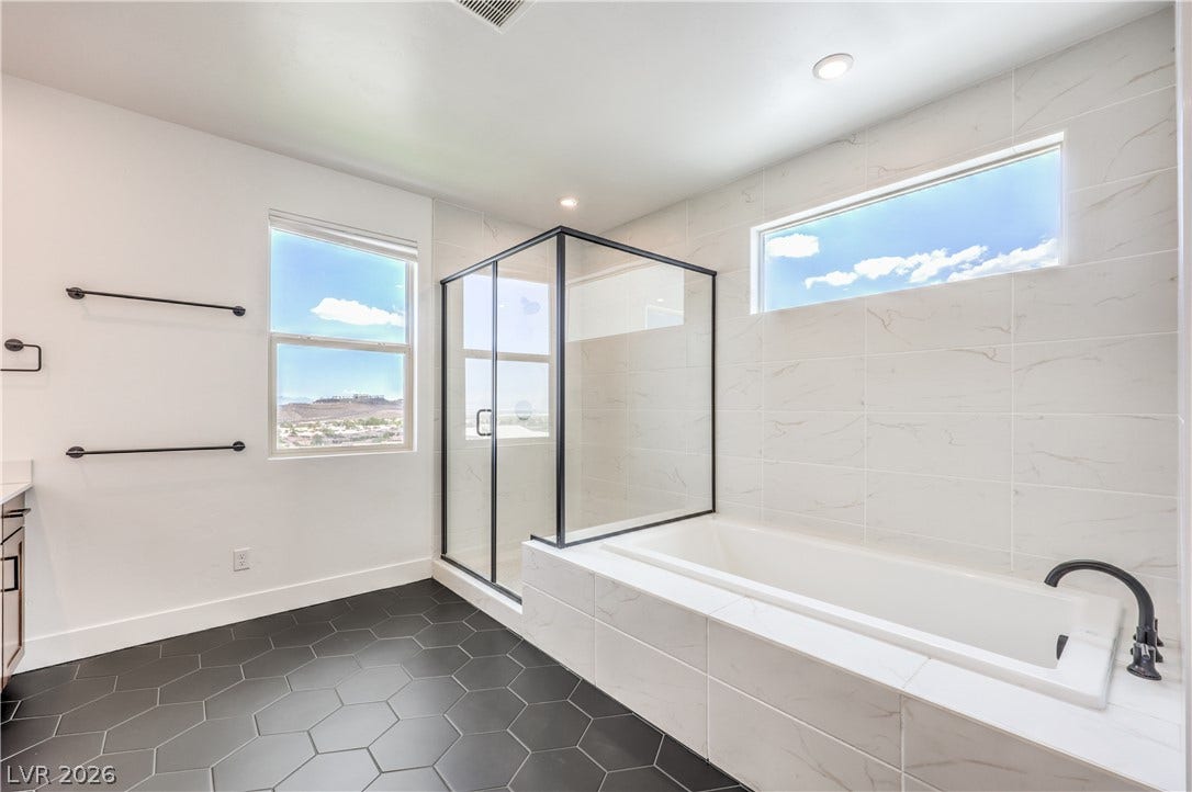 1984 Canyon Highlands Drive, Henderson, NV 89052 A well-lit bathroom featuring a spacious bathtub, a glass-enclosed shower, and sleek hexagon floor tiles.