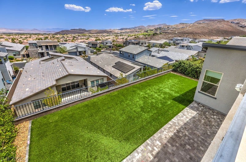 1984 Canyon Highlands Drive, Henderson, NV 89052 An aerial perspective reveals a spacious artificial turf backyard and an inviting paved patio against a scenic desert mountain backdrop.