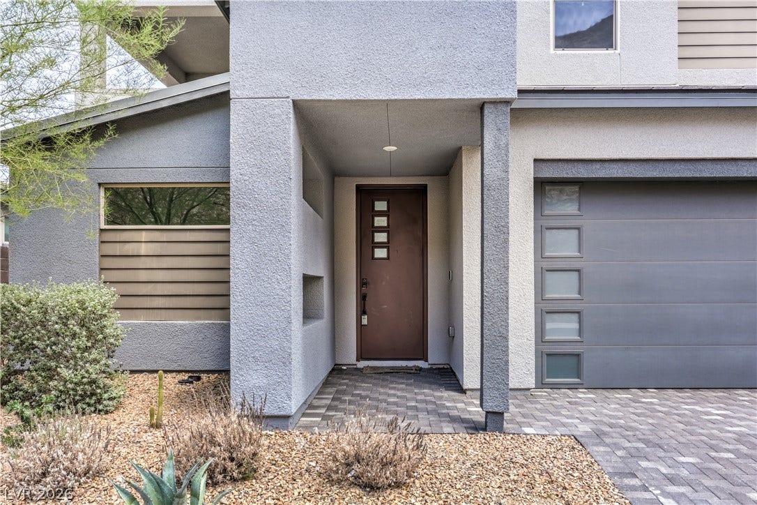1984 Canyon Highlands Drive, Henderson, NV 89052 A contemporary stucco facade with a covered entry and a paver driveway offers inviting curb appeal.