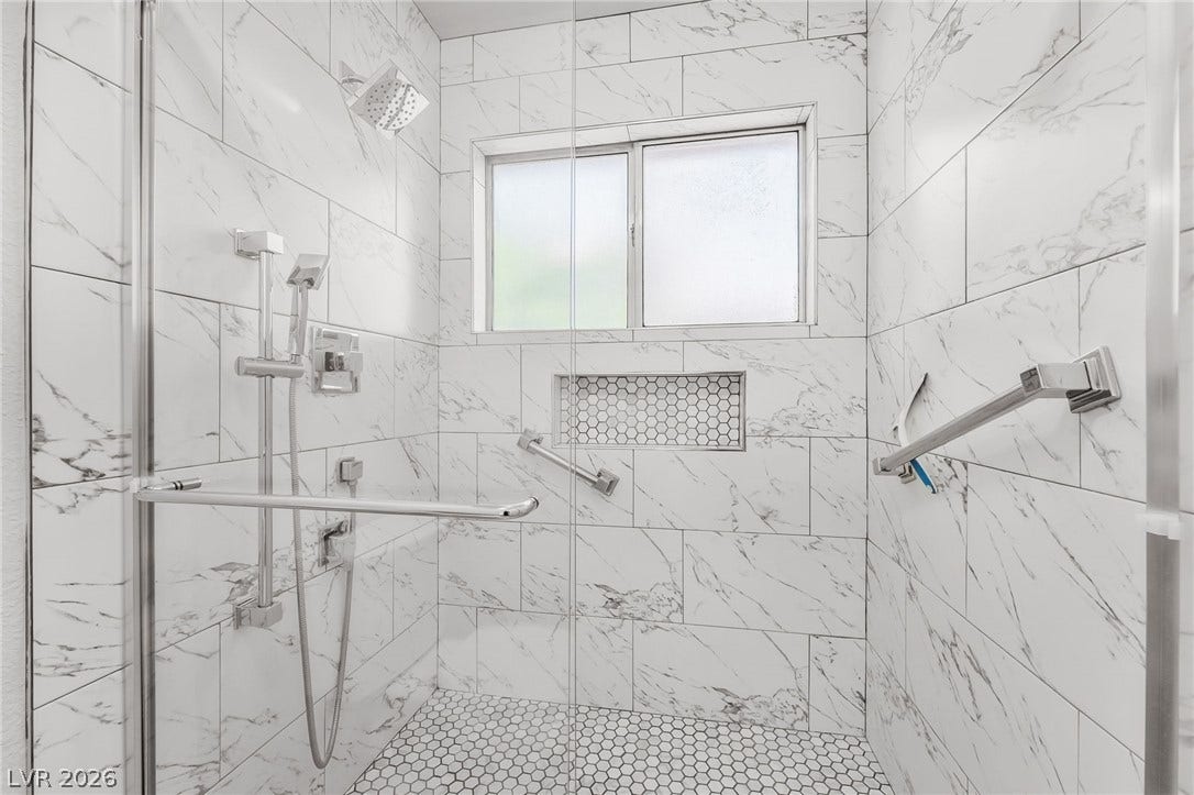 62 Tidwell Lane, Henderson, NV 89074 Gleaming marble-patterned wall tile and a modern glass enclosure define this walk-in shower.