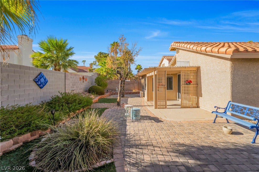 62 Tidwell Lane, Henderson, NV 89074 Brick pavers wind through a landscaped yard with a covered patio under a Spanish tile roof.