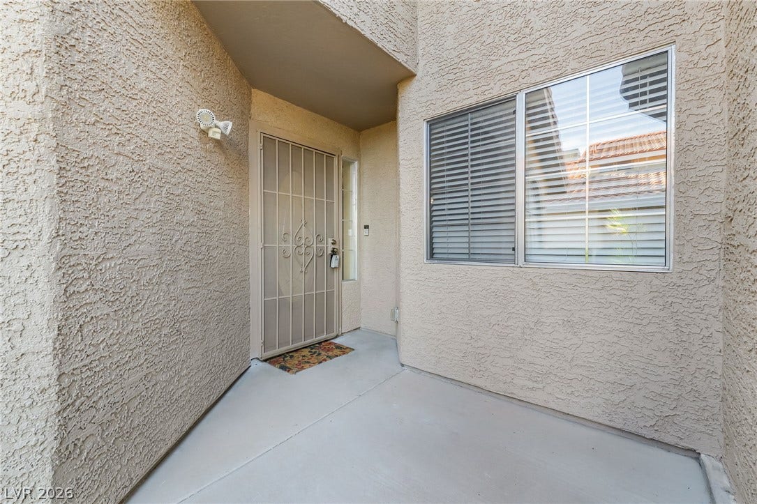 62 Tidwell Lane, Henderson, NV 89074 A recessed covered entrance features textured stucco walls and concrete flooring.