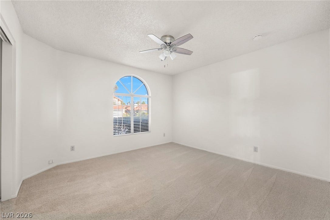62 Tidwell Lane, Henderson, NV 89074 An arched window floods this carpeted bedroom with natural light.