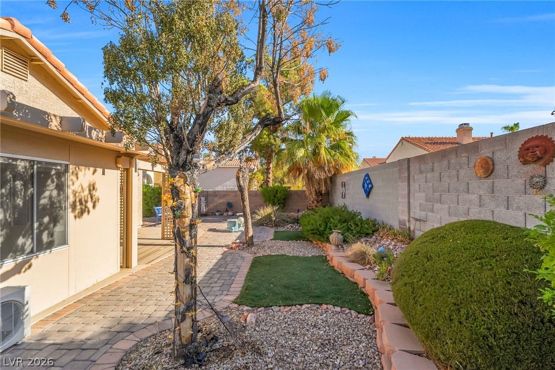 62 Tidwell Lane, Henderson, NV 89074 An inviting backyard walkway wraps alongside a tiled roofline and stone privacy walls.