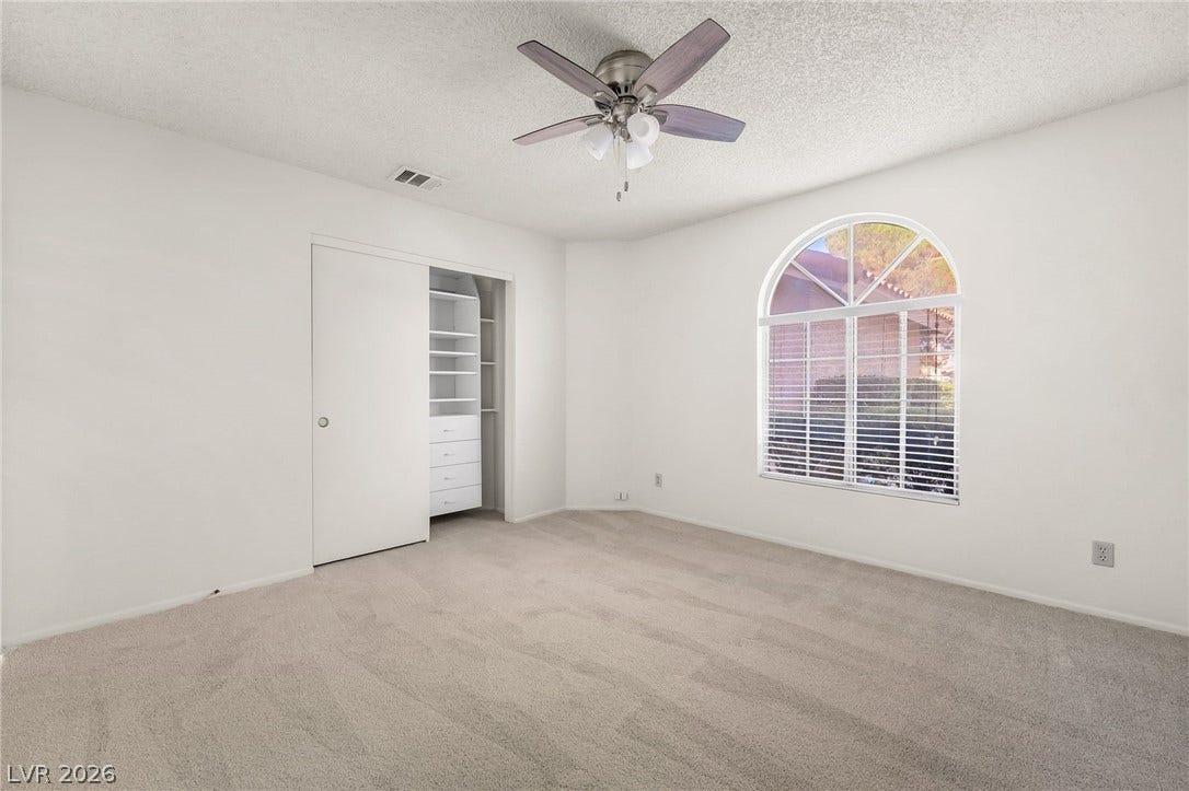 62 Tidwell Lane, Henderson, NV 89074 Plush carpeting anchors this bedroom beneath an arched window and a built-in closet organization system.