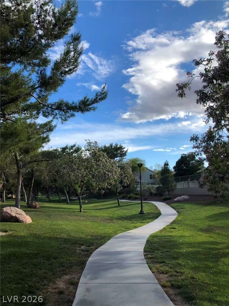 1612 Country Hollow Drive, Las Vegas, NV 89117 A winding concrete pathway meanders through lush green lawns bordered by mature trees.