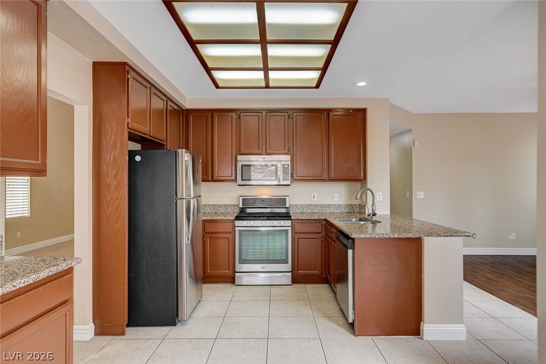 1612 Country Hollow Drive, Las Vegas, NV 89117 A well-appointed kitchen features rich wood cabinetry, granite countertops, and modern stainless steel appliances.