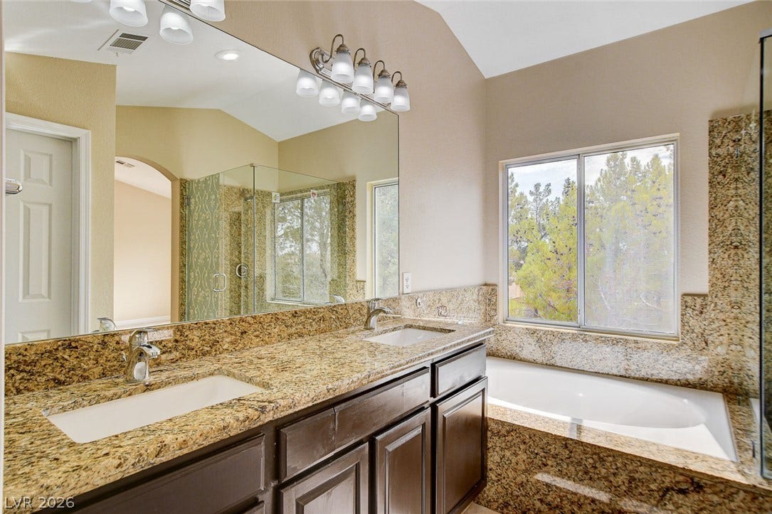 1612 Country Hollow Drive, Las Vegas, NV 89117 Double vanities and a deep soaking tub create a luxurious primary bathroom retreat.