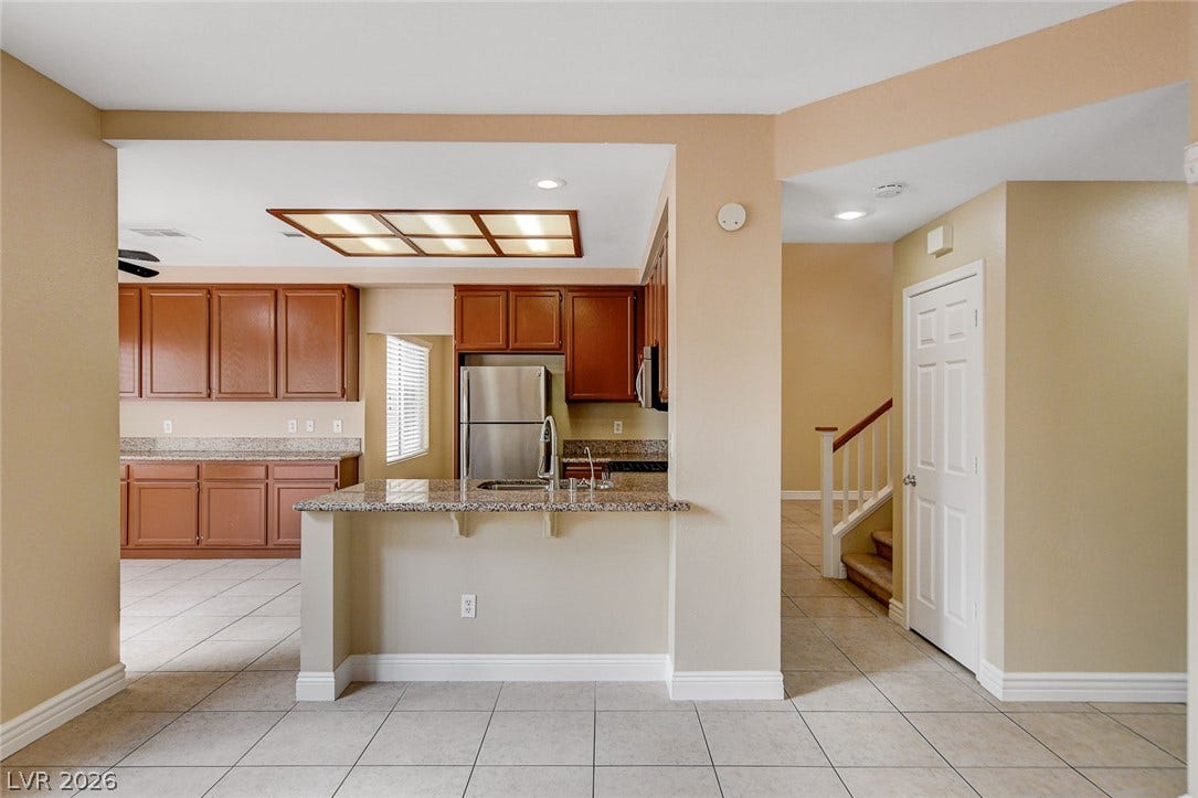 1612 Country Hollow Drive, Las Vegas, NV 89117 An inviting kitchen with granite counters and stainless steel appliances, seamlessly connecting to a bright living space.