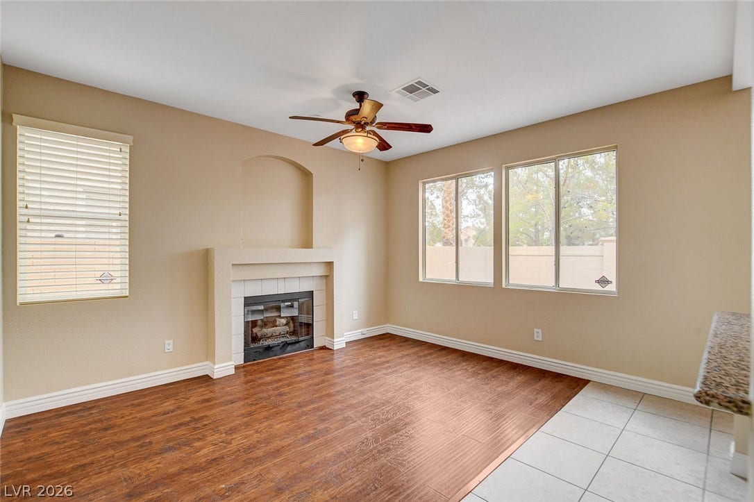 1612 Country Hollow Drive, Las Vegas, NV 89117 A cozy living space features rich hardwood flooring, a charming fireplace, and a ceiling fan for comfort.