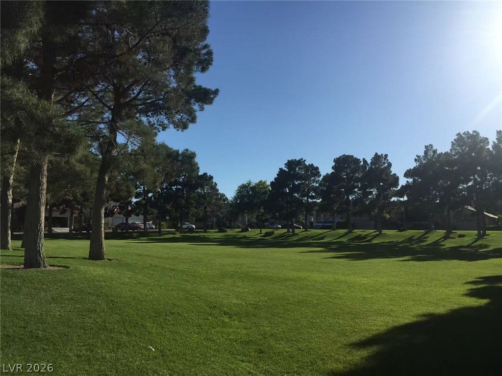1612 Country Hollow Drive, Las Vegas, NV 89117 Mature trees frame a sprawling green lawn under a clear blue sky.