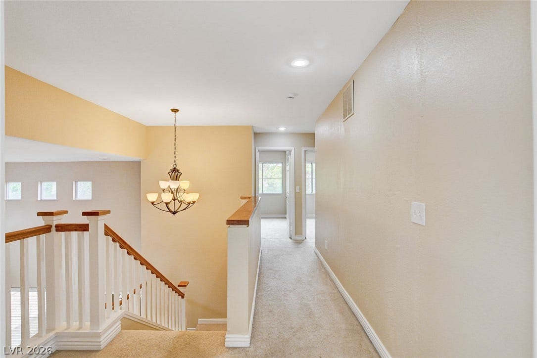 1612 Country Hollow Drive, Las Vegas, NV 89117 A grand chandelier illuminates the landing, showcasing the architectural elegance of the staircase and hallway.