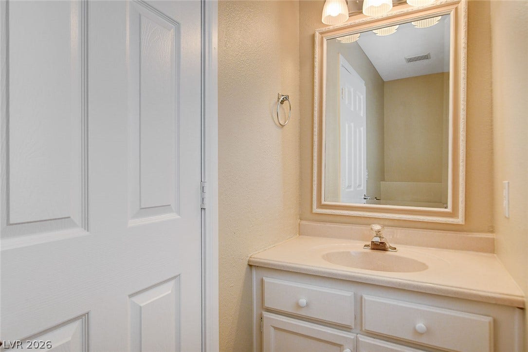 1612 Country Hollow Drive, Las Vegas, NV 89117 A compact vanity with integrated sink and framed mirror creates a functional powder room.