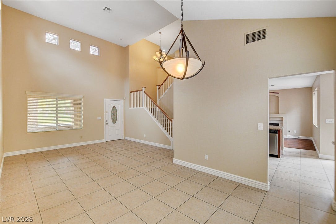 1612 Country Hollow Drive, Las Vegas, NV 89117 An inviting entry opens to a spacious living area featuring soaring ceilings and an elegant staircase.