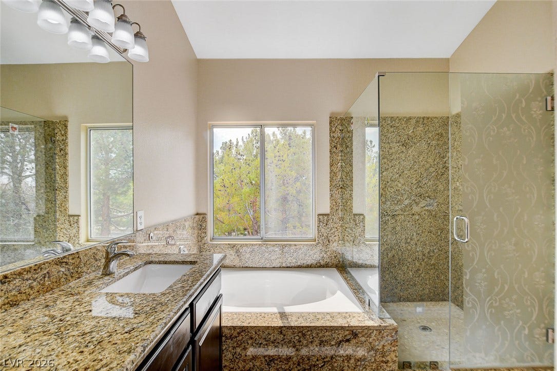 1612 Country Hollow Drive, Las Vegas, NV 89117 Indulge in a tranquil bathing experience in this bathroom featuring a spacious tub, elegant granite finishes, and a glass-enclosed shower.