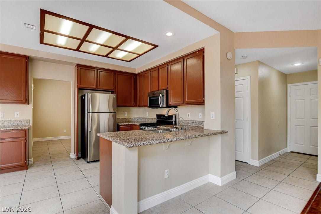 1612 Country Hollow Drive, Las Vegas, NV 89117 A well-equipped kitchen features ample cabinetry, granite counters, and stainless steel appliances.