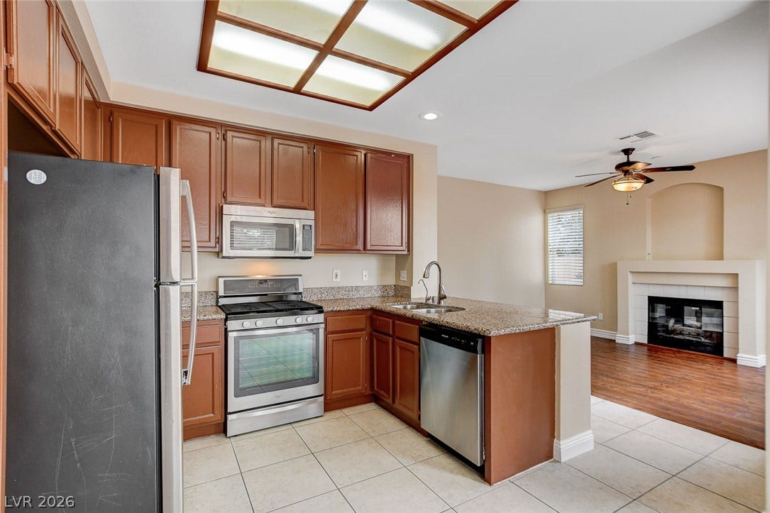 1612 Country Hollow Drive, Las Vegas, NV 89117 A well-appointed kitchen features ample cabinetry and a practical island, flowing into a comfortable living area with a fireplace.