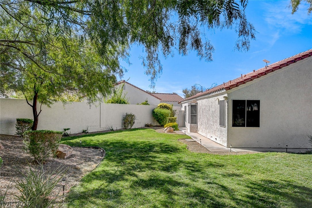 236 Misty Garden Street, Henderson, NV 89012 Mature shade trees and a concrete pathway border the manicured lawn of this enclosed yard.
