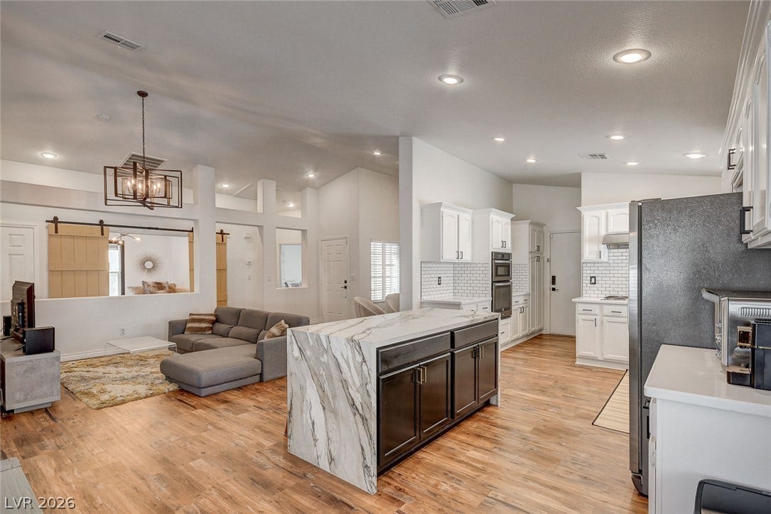 236 Misty Garden Street, Henderson, NV 89012 An open floorplan seamlessly connects the kitchen and living areas over rich wood flooring.