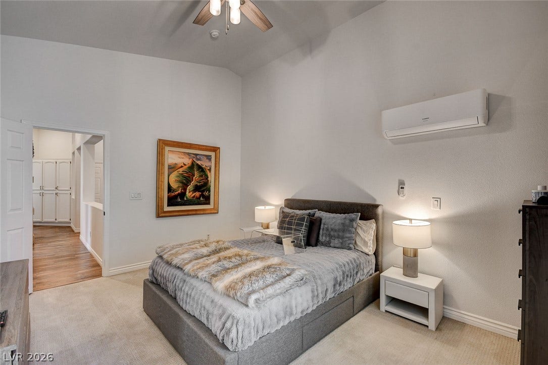 236 Misty Garden Street, Henderson, NV 89012 A spacious bedroom with vaulted ceilings and wall-to-wall carpeting opens to an adjacent hallway.