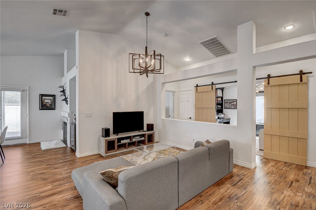 236 Misty Garden Street, Henderson, NV 89012 Rich wood floors and vaulted ceilings frame this open living space featuring a modern chandelier.