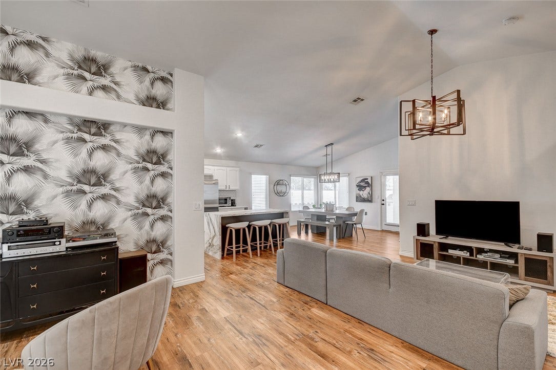 236 Misty Garden Street, Henderson, NV 89012 Rich wood flooring anchors this sprawling open-concept living area beneath soaring vaulted ceilings.