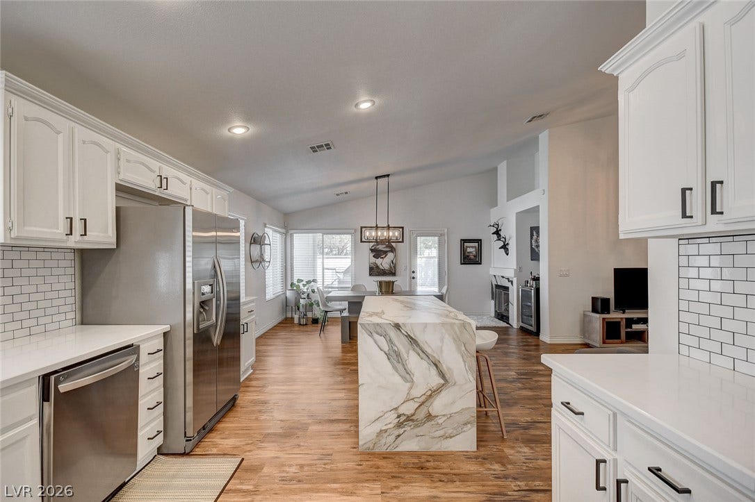 236 Misty Garden Street, Henderson, NV 89012 Warm wood flooring contrasts beautifully with crisp cabinetry and stone countertops in this open kitchen.