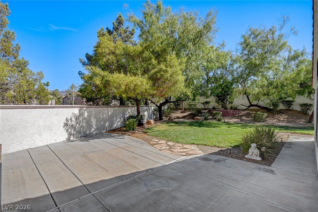236 Misty Garden Street, Henderson, NV 89012 Mature trees shade a manicured lawn and stone pathways bordering a spacious concrete patio.
