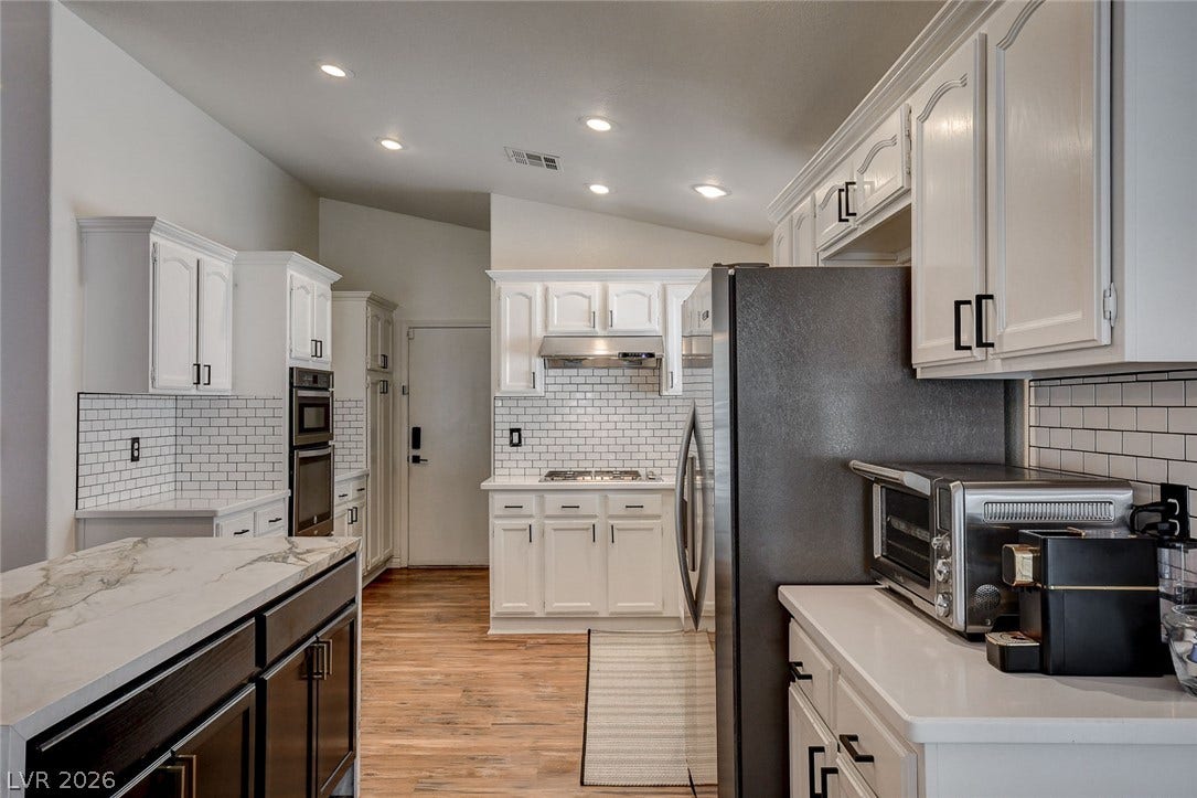236 Misty Garden Street, Henderson, NV 89012 White cabinetry stands out against tile backsplashes and warm wood floors in this updated kitchen.