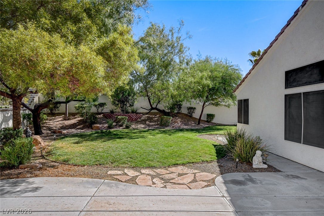 236 Misty Garden Street, Henderson, NV 89012 Mature trees border a circular green lawn and concrete patio space.