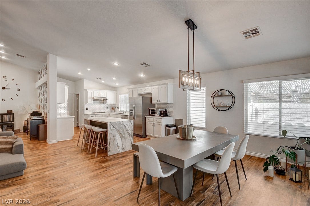 236 Misty Garden Street, Henderson, NV 89012 Rich wood floors seamlessly connect a modern dining space with an open kitchen.