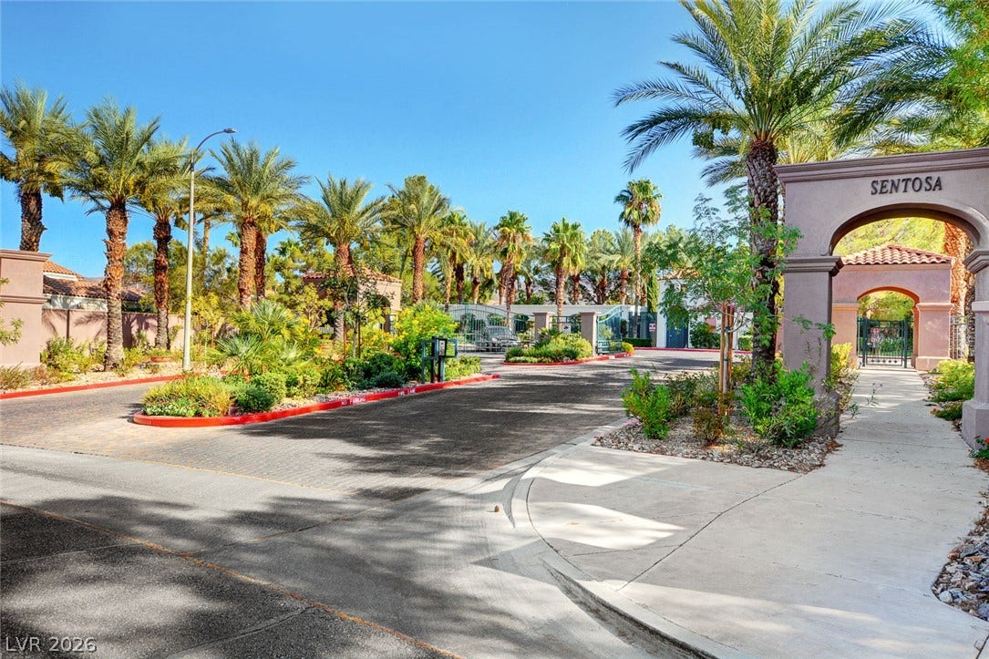 236 Misty Garden Street, Henderson, NV 89012 An arched entry monument and gated roadway lead into a palm-lined residential neighborhood.