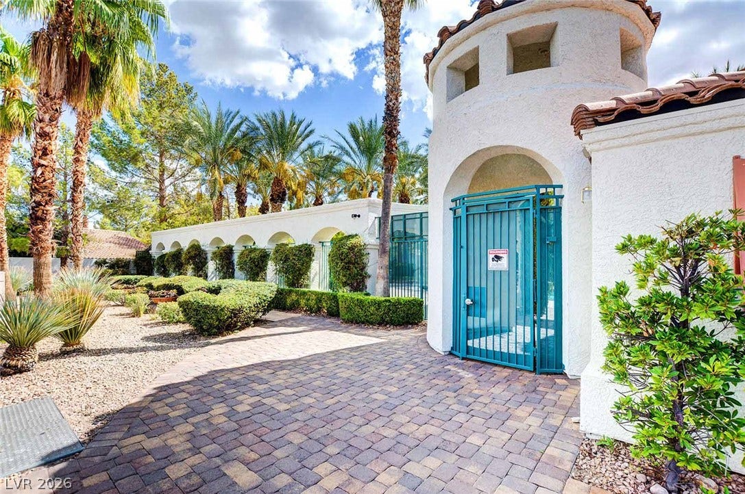 236 Misty Garden Street, Henderson, NV 89012 Mediterranean-inspired entry tower leads past manicured landscaping and a paved courtyard walkway.