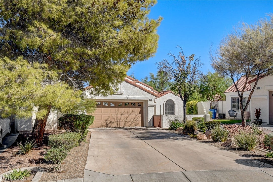 236 Misty Garden Street, Henderson, NV 89012 Mature trees frame a concrete driveway leading to a Spanish tile roof home.