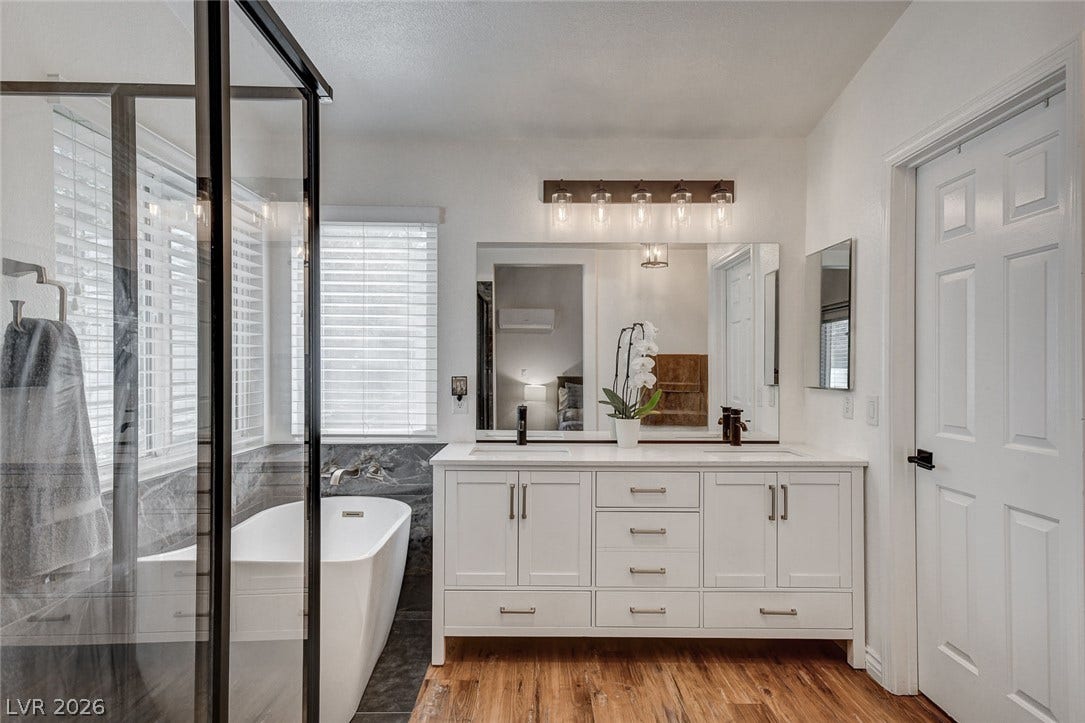236 Misty Garden Street, Henderson, NV 89012 Rich wood flooring contrasts beautifully with a white double vanity and freestanding soaking tub.