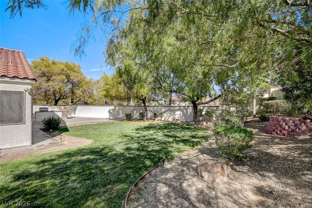 236 Misty Garden Street, Henderson, NV 89012 Mature trees shade a spacious green lawn bordered by a privacy wall and paved patio.