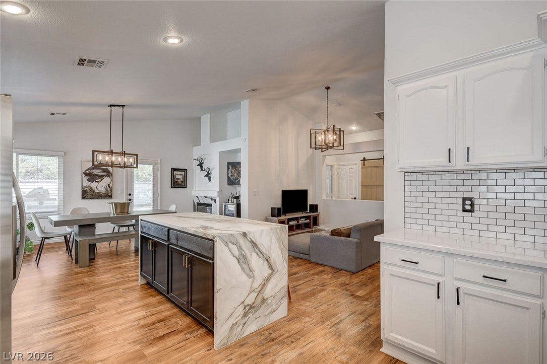 236 Misty Garden Street, Henderson, NV 89012 Warm wood flooring grounds this open concept space with an eye-catching waterfall marble island.