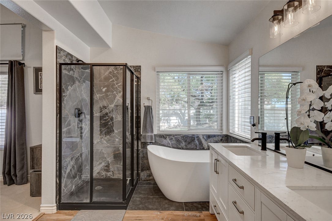 236 Misty Garden Street, Henderson, NV 89012 Polished stone tiling and a modern freestanding tub ground this elegant primary bath sanctuary.