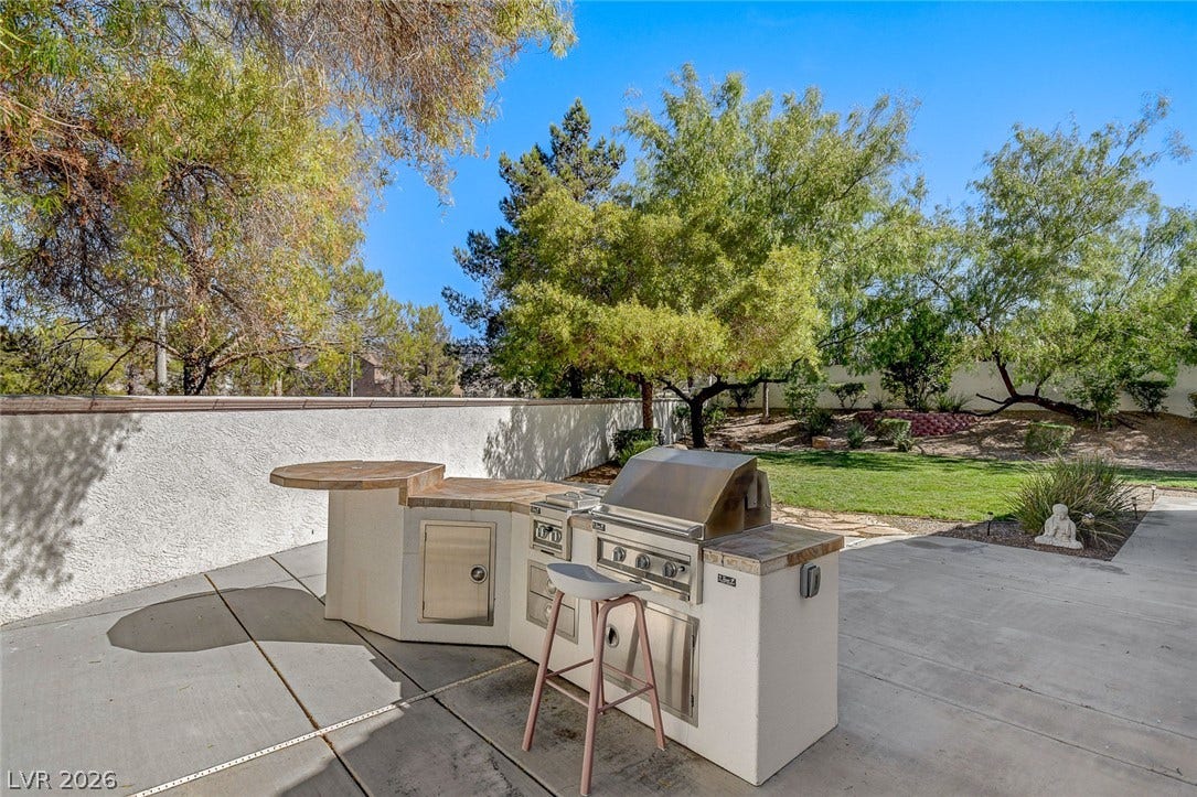236 Misty Garden Street, Henderson, NV 89012 An outdoor kitchen with a built-in grill anchors the concrete patio beside the grassy yard.