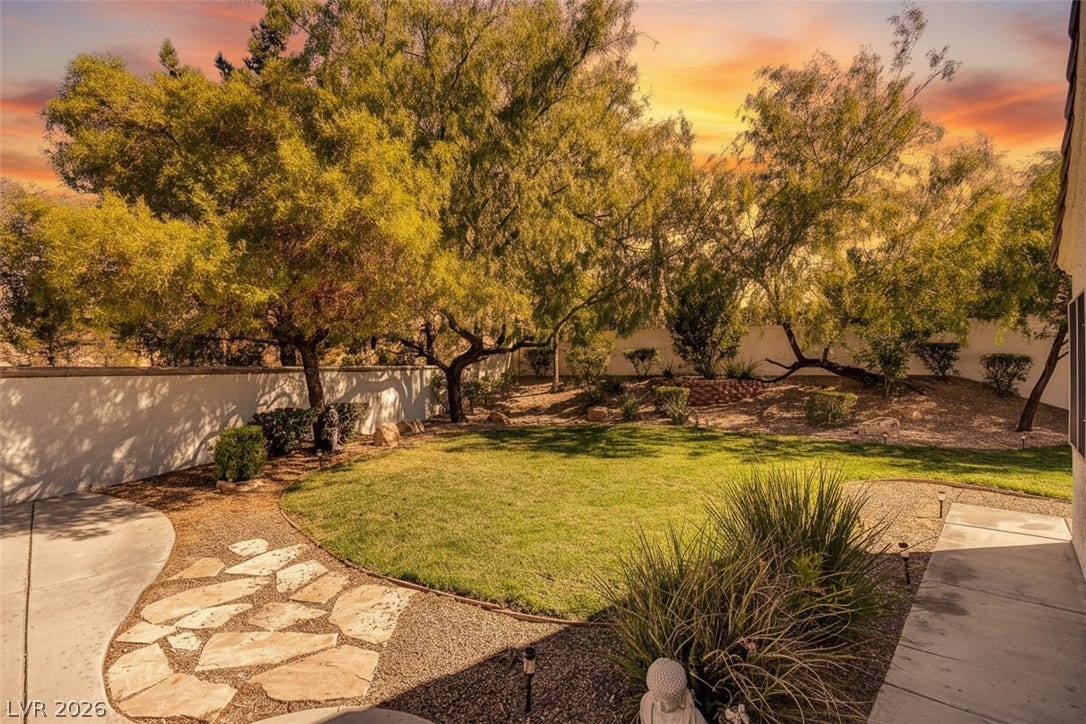236 Misty Garden Street, Henderson, NV 89012 Mature trees frame a manicured lawn and stone pathways in this private backyard.