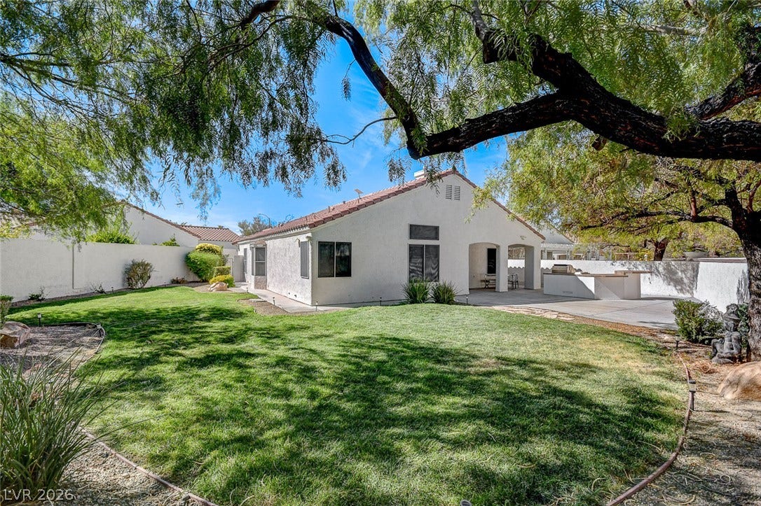 236 Misty Garden Street, Henderson, NV 89012 Mature trees shade a manicured lawn leading to a spacious covered patio and outdoor kitchen.