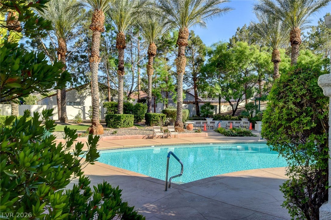 236 Misty Garden Street, Henderson, NV 89012 Lush palm trees and manicured shrubbery frame a pristine concrete pool deck.