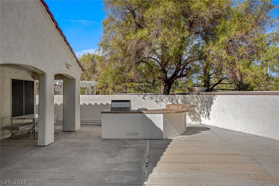 236 Misty Garden Street, Henderson, NV 89012 A spacious concrete patio features a built-in barbecue station alongside a stucco exterior wall.